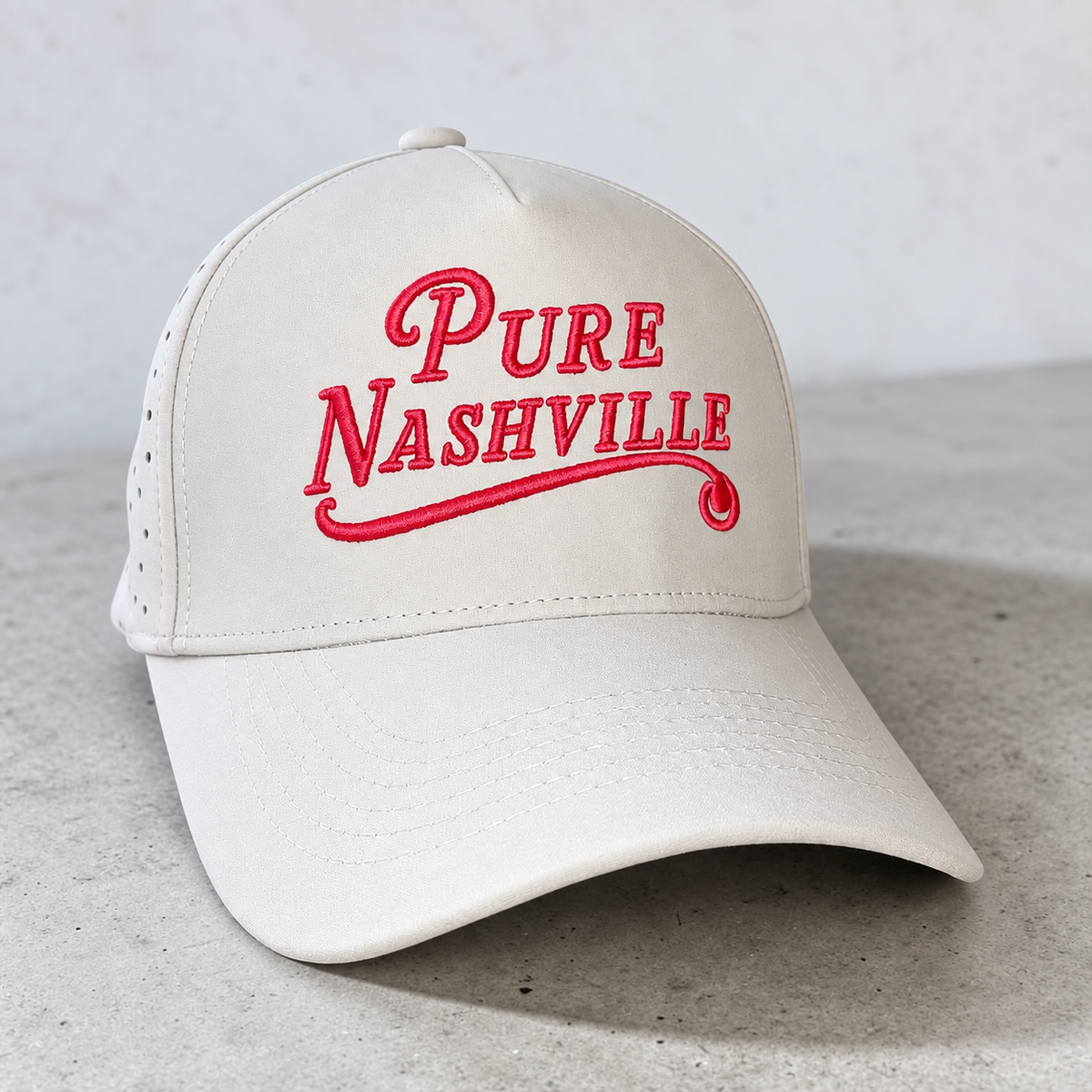 Cream performance hat with red Pure Nashville embroidery and laser-cut side venting