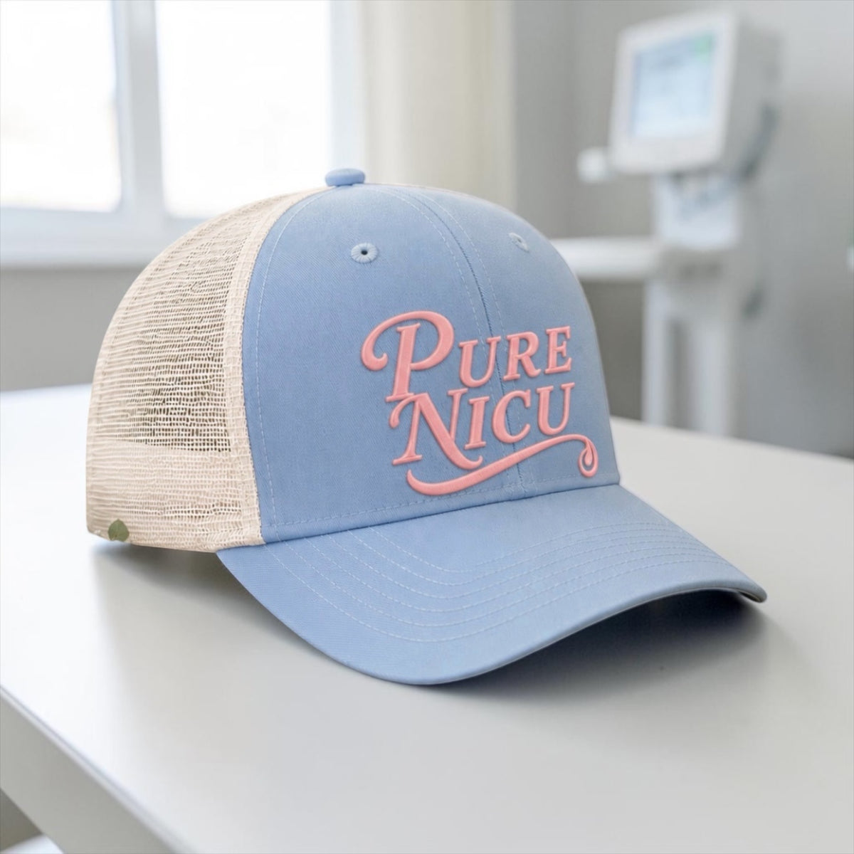 Pure NICU Trucker Hat in Baby Blue and Khaki with pink puff embroidery, set in a hospital room