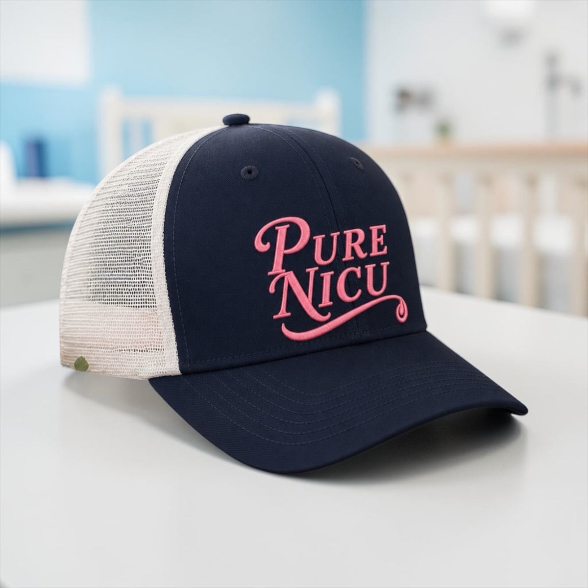 Pure NICU Trucker Hat in Navy and White with pink puff embroidery, set in a hospital room